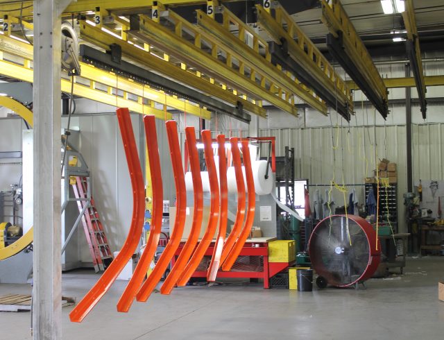 powder coated orange parts sitting in front of fan at blue lake industries